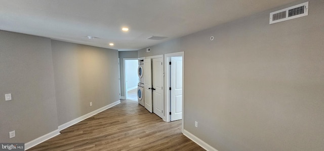 hallway with stacked washer / dryer and light wood-type flooring