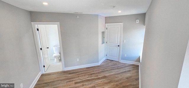 unfurnished bedroom with electric panel, wood-type flooring, and ensuite bath