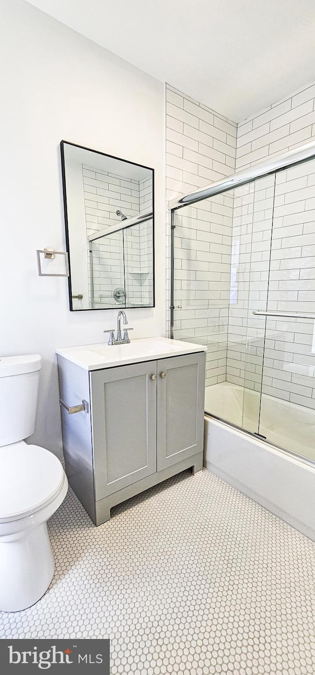 full bathroom featuring tile patterned floors, vanity, combined bath / shower with glass door, and toilet