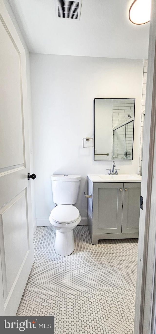 bathroom featuring toilet, an enclosed shower, and vanity