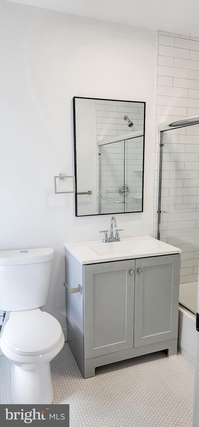 full bathroom featuring toilet, bath / shower combo with glass door, vanity, and tile patterned flooring