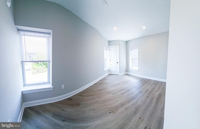 empty room with hardwood / wood-style flooring, a healthy amount of sunlight, and lofted ceiling