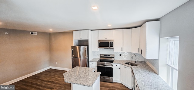 kitchen with a center island, sink, light stone countertops, and stainless steel appliances