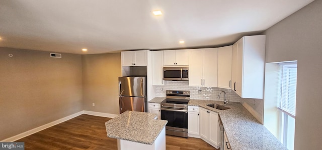 kitchen featuring a kitchen island, sink, light stone counters, and stainless steel appliances