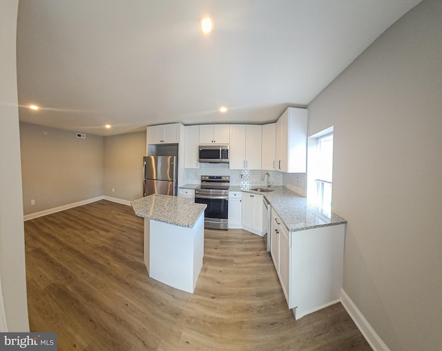 kitchen with a center island, white cabinets, light hardwood / wood-style flooring, sink, and appliances with stainless steel finishes