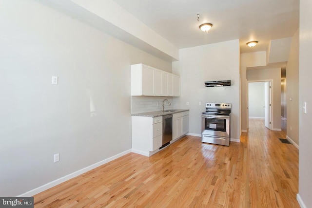 kitchen with stainless steel appliances, white cabinets, sink, light wood-type flooring, and range hood