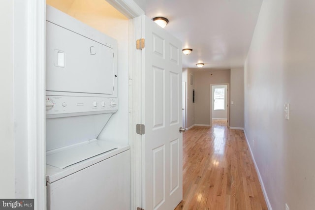 laundry area featuring stacked washer and clothes dryer and light wood-type flooring