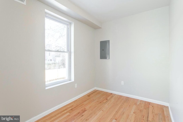 empty room with electric panel and light hardwood / wood-style floors