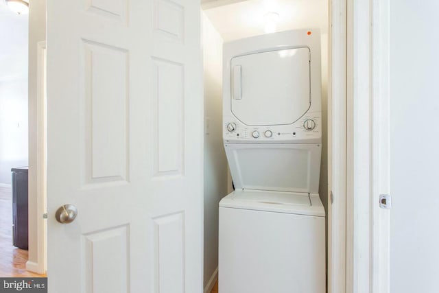 clothes washing area featuring stacked washing maching and dryer and hardwood / wood-style flooring