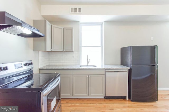 kitchen with gray cabinets, appliances with stainless steel finishes, light hardwood / wood-style floors, and range hood