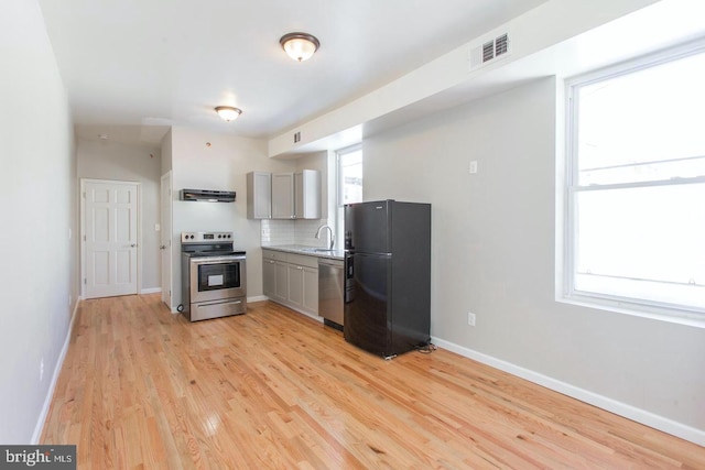 kitchen with light hardwood / wood-style floors, extractor fan, appliances with stainless steel finishes, tasteful backsplash, and gray cabinetry