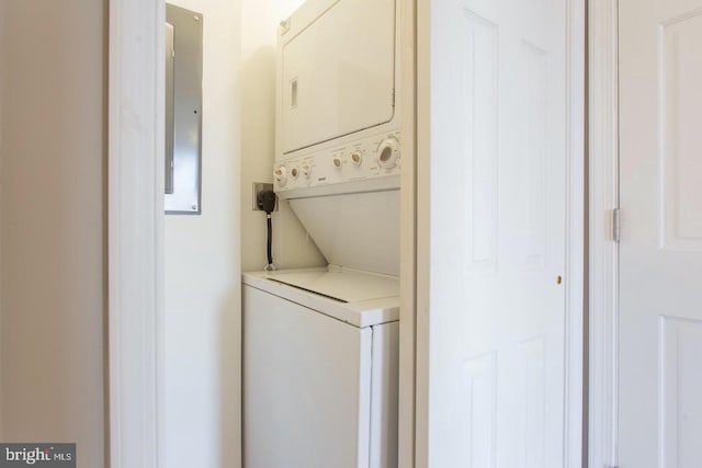 clothes washing area featuring stacked washing maching and dryer and electric panel