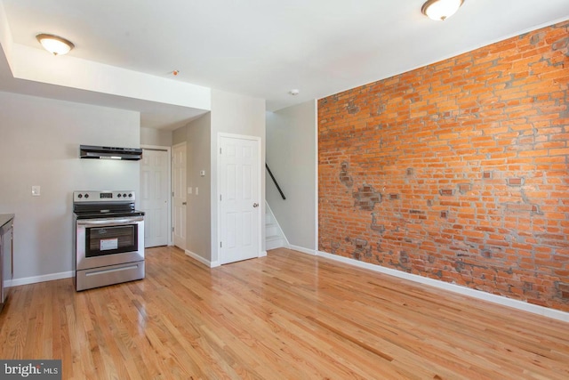 kitchen with brick wall, stainless steel electric range, extractor fan, and light wood-type flooring