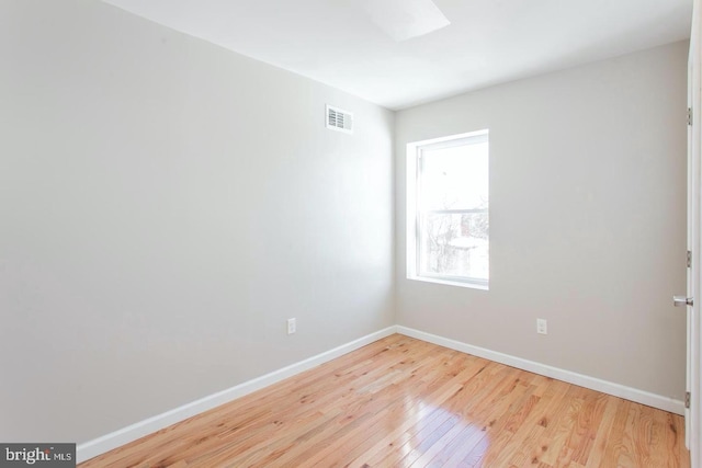 spare room featuring a skylight and light hardwood / wood-style flooring