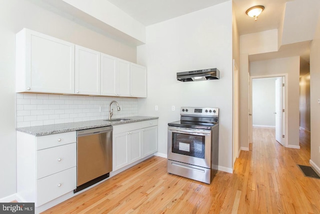 kitchen featuring white cabinetry, extractor fan, appliances with stainless steel finishes, light hardwood / wood-style flooring, and decorative backsplash