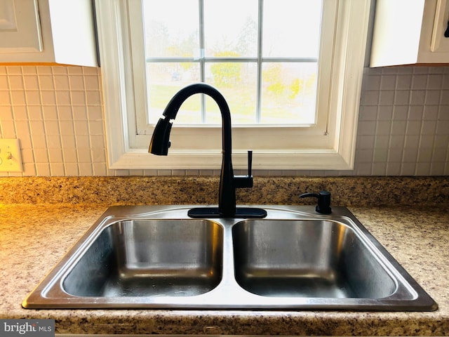 room details featuring sink, white cabinets, and stone countertops