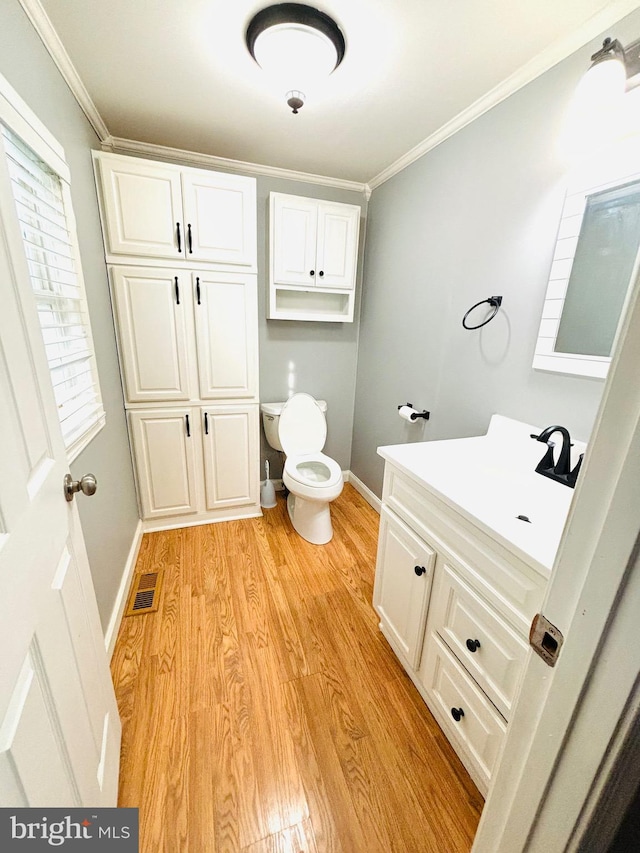 bathroom featuring toilet, vanity, ornamental molding, and hardwood / wood-style flooring