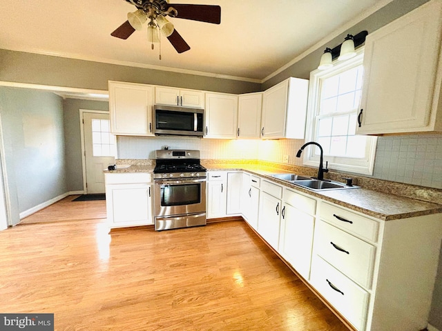 kitchen featuring white cabinets, appliances with stainless steel finishes, a wealth of natural light, and sink