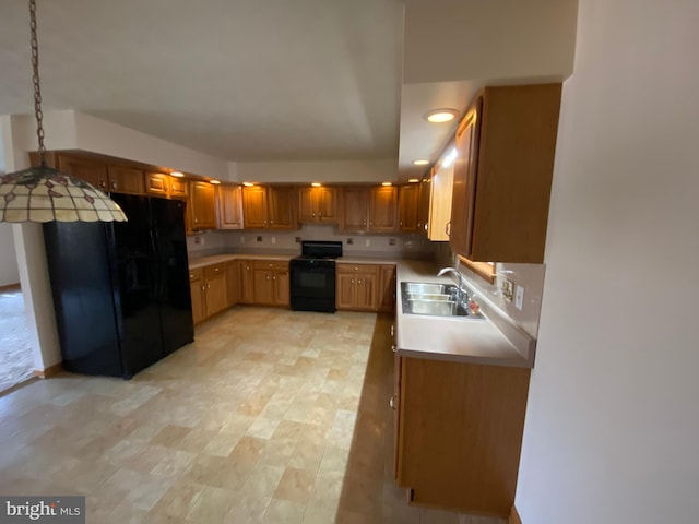 kitchen with hanging light fixtures, sink, black appliances, and light hardwood / wood-style flooring