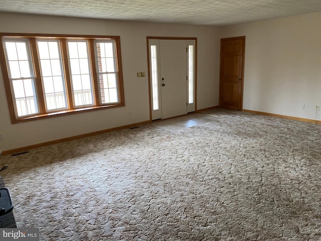 carpeted entryway featuring a textured ceiling