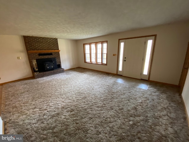 unfurnished living room featuring a brick fireplace, a textured ceiling, and carpet