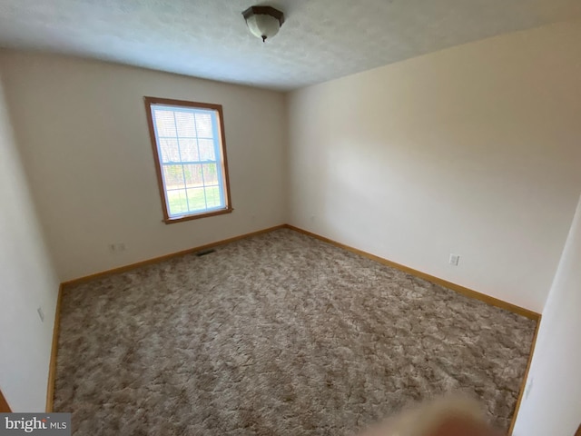 carpeted empty room with a textured ceiling