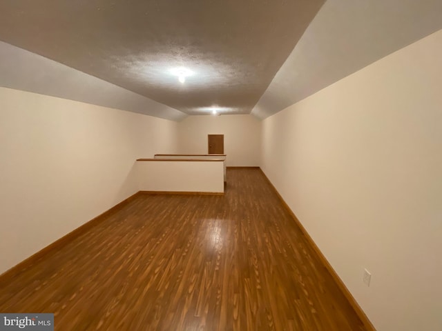 bonus room with vaulted ceiling and dark hardwood / wood-style floors