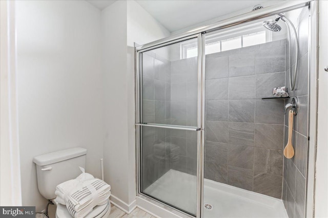 bathroom featuring toilet and a shower with shower door