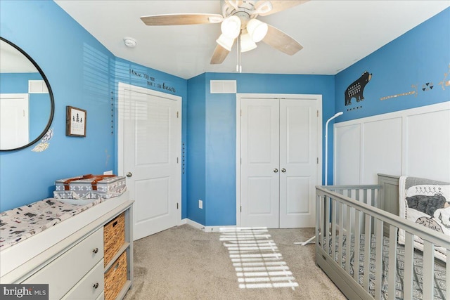 carpeted bedroom featuring ceiling fan, a crib, and a closet