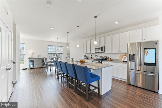 kitchen with a center island with sink, white cabinets, a kitchen bar, and stainless steel appliances