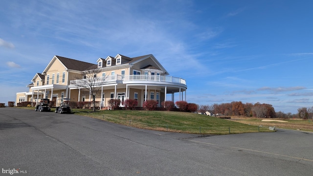 view of front facade with a front yard, a porch, and a balcony