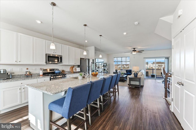 kitchen with white cabinets, stainless steel appliances, and a kitchen island with sink