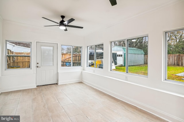 unfurnished sunroom featuring ceiling fan and plenty of natural light