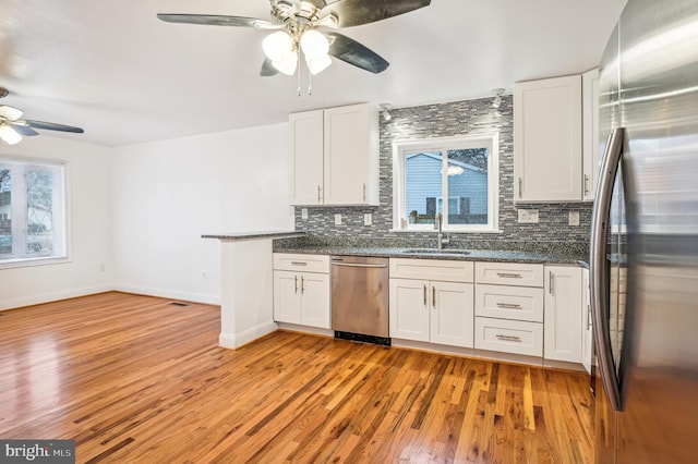 kitchen featuring backsplash, stainless steel appliances, sink, light hardwood / wood-style flooring, and white cabinetry