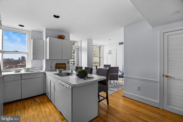 kitchen featuring decorative light fixtures, gray cabinets, kitchen peninsula, sink, and white dishwasher