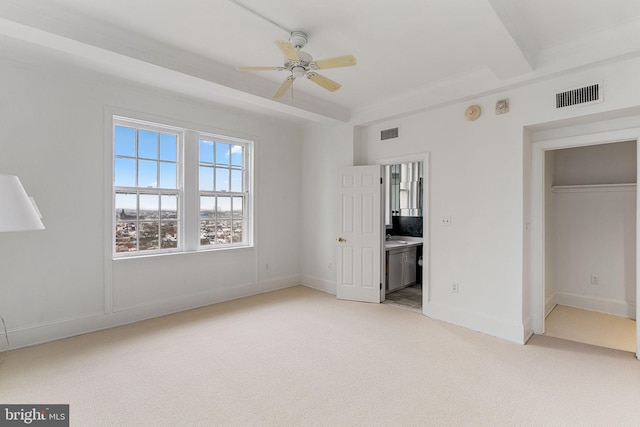 unfurnished bedroom featuring light carpet, ceiling fan, a closet, and ensuite bath