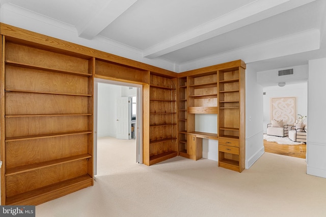 unfurnished living room featuring crown molding, carpet flooring, built in desk, beam ceiling, and built in shelves