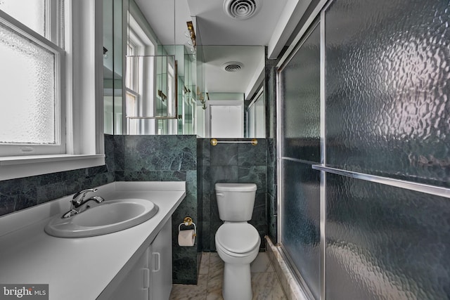 bathroom with a shower with shower door, tile walls, plenty of natural light, and toilet