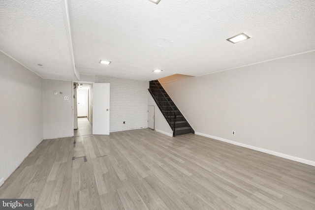 unfurnished living room with light hardwood / wood-style flooring and a textured ceiling