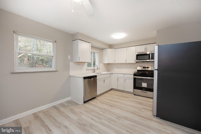 kitchen featuring white cabinetry, appliances with stainless steel finishes, a healthy amount of sunlight, and sink