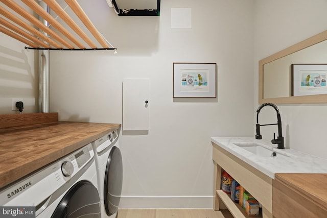 laundry area featuring light wood-type flooring, sink, and independent washer and dryer