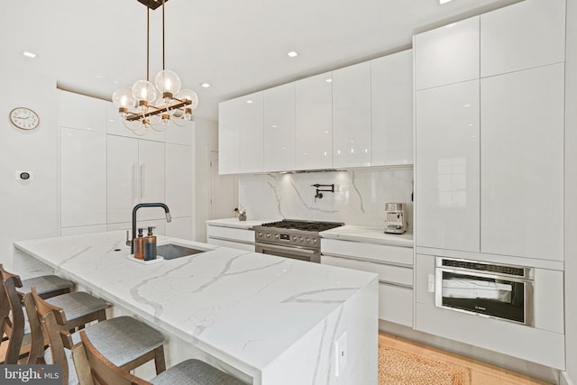 kitchen featuring sink, appliances with stainless steel finishes, decorative light fixtures, white cabinets, and decorative backsplash