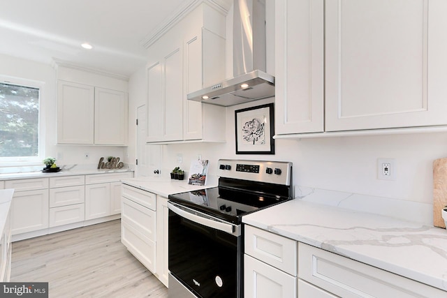 kitchen with stainless steel electric stove, white cabinets, light hardwood / wood-style flooring, wall chimney exhaust hood, and light stone countertops