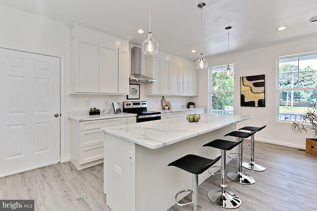 kitchen with a center island, hanging light fixtures, wall chimney range hood, electric stove, and white cabinets