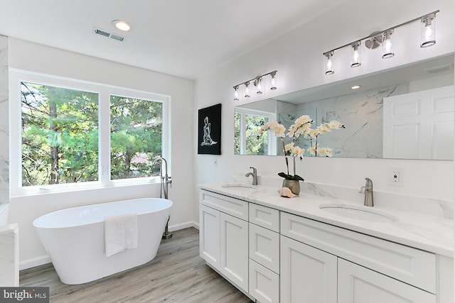 bathroom with hardwood / wood-style flooring, vanity, and a tub