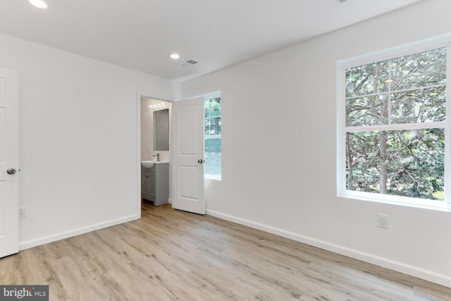 unfurnished bedroom with light hardwood / wood-style floors and connected bathroom