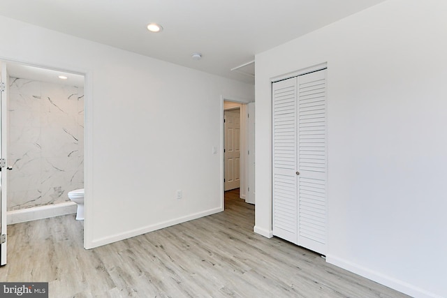 unfurnished bedroom with connected bathroom, a closet, and light hardwood / wood-style flooring