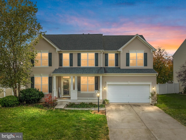 view of property featuring a garage, a lawn, and covered porch