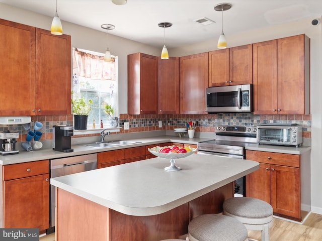 kitchen with backsplash, appliances with stainless steel finishes, sink, a breakfast bar area, and light hardwood / wood-style flooring