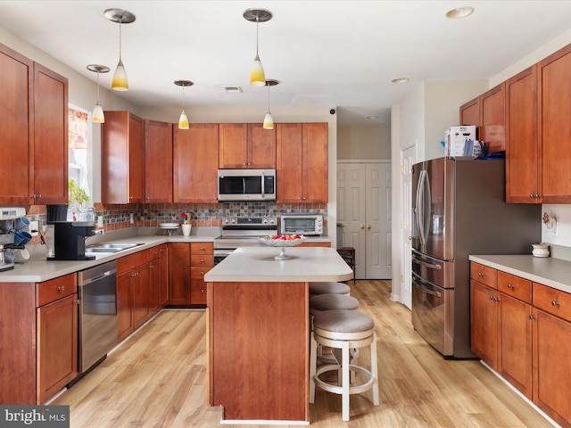 kitchen with a kitchen breakfast bar, appliances with stainless steel finishes, light hardwood / wood-style floors, and a center island